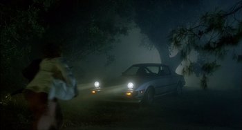 Movie still from “The Howling” (1981), directed by Joe Dante – A couple of cars driving down a street at night; Wide shot, High angle