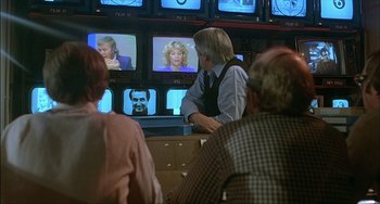 Movie still from “The Howling” (1981), directed by Joe Dante – A group of people sitting in front of a television; Medium shot, Over the shoulder angle