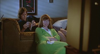 Movie still from “The Howling” (1981), directed by Joe Dante – A woman sitting on a couch in front of a television; Medium shot, High angle