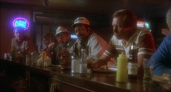 Movie still from “The Howling” (1981), directed by Joe Dante – A group of men sitting at a bar drinking beer; Medium shot, High angle