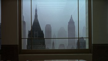 Movie still from “The Hudsucker Proxy” (1994), directed by Ethan Coen – A view of a city skyline through a window; Extreme Wide shot, Low angle