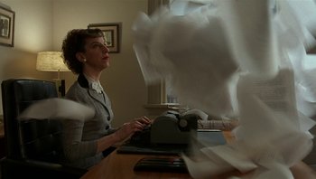 Movie still from “The Hudsucker Proxy” (1994), directed by Ethan Coen – A woman sitting at a desk typing on a typewriter; Medium shot, Low angle