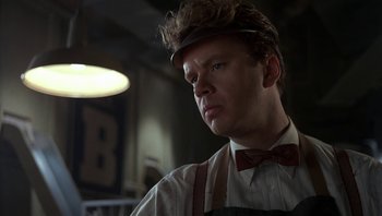 Movie still from “The Hudsucker Proxy” (1994), directed by Ethan Coen – A person wearing an apron and a bow tie; Close Up shot, Low angle