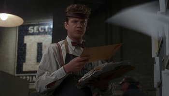 Movie still from “The Hudsucker Proxy” (1994), directed by Ethan Coen – A man holding a piece of paper in his hands; Medium shot, Low angle