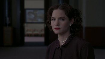 Movie still from “The Hudsucker Proxy” (1994), directed by Ethan Coen – A woman in a brown jacket and a pearl necklace; Close Up shot, Over the shoulder angle