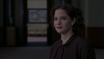 Movie still from “The Hudsucker Proxy” (1994), directed by Ethan Coen – A woman in a black dress and a pearl necklace; Close Up shot, Over the shoulder angle