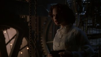Movie still from “The Hudsucker Proxy” (1994), directed by Ethan Coen – A woman in a white shirt is standing next to a chain; Medium shot, Low angle