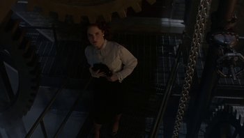 Movie still from “The Hudsucker Proxy” (1994), directed by Ethan Coen – A woman standing on some stairs holding a purse; Wide shot, Overhead angle