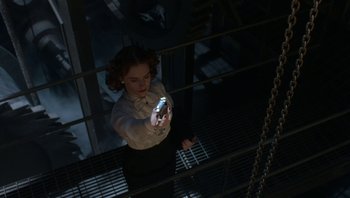 Movie still from “The Hudsucker Proxy” (1994), directed by Ethan Coen – A woman holding a cell phone while standing in a room; Medium shot, Overhead angle