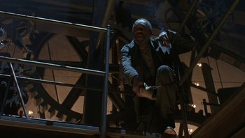 Movie still from “The Hudsucker Proxy” (1994), directed by Ethan Coen – A man standing on top of a metal railing; Wide shot, Low angle