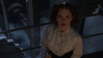 Movie still from “The Hudsucker Proxy” (1994), directed by Ethan Coen – A woman in a white shirt and black skirt; Medium shot, Low angle