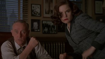 Movie still from “The Hudsucker Proxy” (1994), directed by Ethan Coen – A man and a woman sitting at a dinner table; Medium shot, Low angle