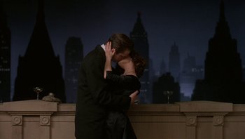 Movie still from “The Hudsucker Proxy” (1994), directed by Ethan Coen – A man and a woman kissing in front of a city skyline; Medium shot, Low angle