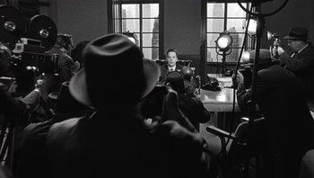 Movie still from “The Hudsucker Proxy” (1994), directed by Ethan Coen – A group of people sitting around a table; Medium shot, Over the shoulder angle