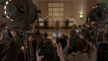 Movie still from “The Hudsucker Proxy” (1994), directed by Ethan Coen – A group of people standing in front of a camera; Wide shot, Low angle