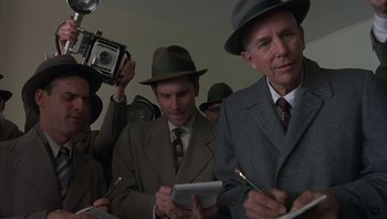 Movie still from “The Hudsucker Proxy” (1994), directed by Ethan Coen – A group of men in suits and hats writing on papers; Medium shot, Low angle