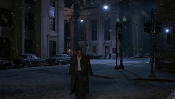 Movie still from “The Hudsucker Proxy” (1994), directed by Ethan Coen – A man standing in the middle of a street at night; Wide shot, High angle