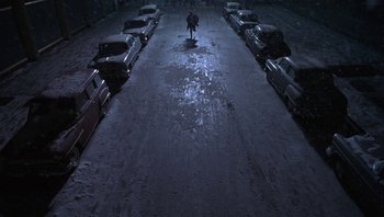 Movie still from “The Hudsucker Proxy” (1994), directed by Ethan Coen – A person walking down a street in the dark; Extreme Wide shot, Overhead angle