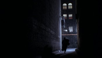 Movie still from “The Hudsucker Proxy” (1994), directed by Ethan Coen – A person walking down a street with an umbrella in the rain; Extreme Wide shot, Low angle