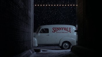 Movie still from “The Hudsucker Proxy” (1994), directed by Ethan Coen – A van parked in a parking lot at night; Wide shot, High angle