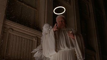 Movie still from “The Hudsucker Proxy” (1994), directed by Ethan Coen – An old man dressed as an angel holding a cigarette; Medium shot, Low angle