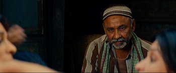 Movie still from “The Hundred-Foot Journey” (2014), directed by Lasse Hallström – An older man wearing a head scarf and a striped shirt; Close Up shot, Over the shoulder angle
