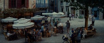 Movie still from “The Hundred-Foot Journey” (2014), directed by Lasse Hallström – A group of people sitting at tables on a sidewalk; Extreme Wide shot, High angle