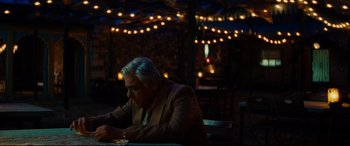 Movie still from “The Hundred-Foot Journey” (2014), directed by Lasse Hallström – An older man sitting at a table with a plate of food in front of him; Medium shot, Over the shoulder angle