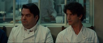 Movie still from “The Hundred-Foot Journey” (2014), directed by Lasse Hallström – Two men in chef's whites sitting next to each other; Close Up shot, Over the shoulder angle