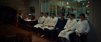 Movie still from “The Hundred-Foot Journey” (2014), directed by Lasse Hallström – A group of men sitting in a row in a room; Wide shot, High angle