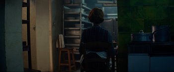 Movie still from “The Hundred-Foot Journey” (2014), directed by Lasse Hallström – A woman sitting in a chair in front of shelves; Medium shot, Over the shoulder angle