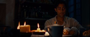 Movie still from “The Hundred-Foot Journey” (2014), directed by Lasse Hallström – A man sitting at a table with candles in front of him; Medium shot, Over the shoulder angle
