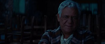 Movie still from “The Hundred-Foot Journey” (2014), directed by Lasse Hallström – An older man sitting in front of a wooden chair; Close Up shot, Over the shoulder angle