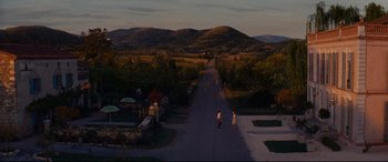 Movie still from “The Hundred-Foot Journey” (2014), directed by Lasse Hallström – Two people walking down a road near a field; Extreme Wide shot, High angle