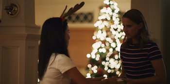 Movie still from “Press Play” (2022), directed by Greg Björkman – Two young girls standing in front of a christmas tree; Medium shot, Over the shoulder angle