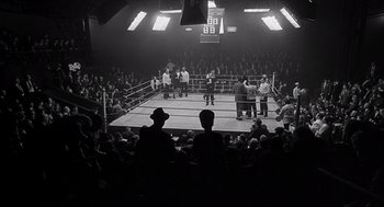 A boxing match in a boxing ring with spectators watching it