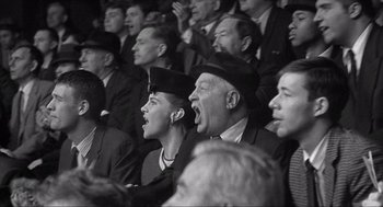 Movie still from “The Hurricane” (1999), directed by Norman Jewison – A group of men and women sitting in a stadium; Medium shot, Low angle