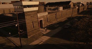 Movie still from “The Hurricane” (1999), directed by Norman Jewison – A person standing on a sidewalk near a building; Extreme Wide shot, High angle