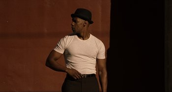 Movie still from “The Hurricane” (1999), directed by Norman Jewison – A man wearing a white shirt and a black hat; Medium shot, Low angle
