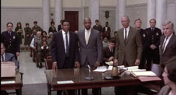 Movie still from “The Hurricane” (1999), directed by Norman Jewison – A group of men standing in front of a wooden table; Wide shot, High angle