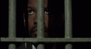 Movie still from “The Hurricane” (1999), directed by Norman Jewison – A person behind a metal fence; Close Up shot, Low angle