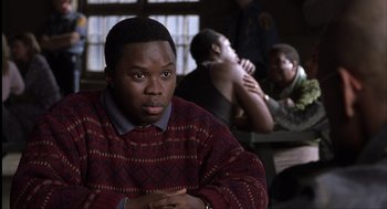 Movie still from “The Hurricane” (1999), directed by Norman Jewison – A man in a red and black sweater sitting in front of two other men; Close Up shot, Over the shoulder angle