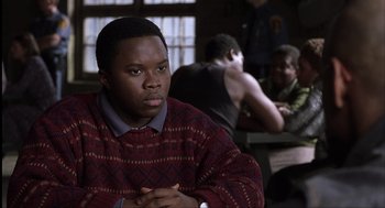 Movie still from “The Hurricane” (1999), directed by Norman Jewison – A man sitting in front of other people in a room; Close Up shot, Over the shoulder angle