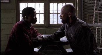 Movie still from “The Hurricane” (1999), directed by Norman Jewison – Two men sitting at a table talking to each other; Medium shot, Over the shoulder angle