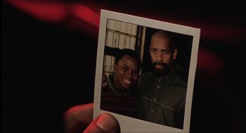 Movie still from “The Hurricane” (1999), directed by Norman Jewison – A man holding a polaroid of a man and a woman; Close Up shot, Low angle