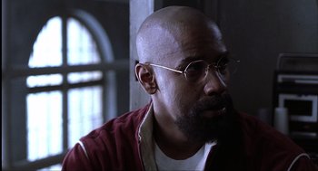 Movie still from “The Hurricane” (1999), directed by Norman Jewison – A man with a beard wearing glasses and a red jacket; Close Up shot, Low angle