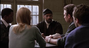 Movie still from “The Hurricane” (1999), directed by Norman Jewison – A man and two women sitting at a table talking; Medium shot, Over the shoulder angle