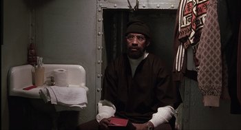Movie still from “The Hurricane” (1999), directed by Norman Jewison – A man sitting on a chair in a jail cell; Medium shot, High angle