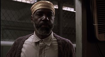 Movie still from “The Hurricane” (1999), directed by Norman Jewison – A man with a beard wearing a hat and a shirt; Close Up shot, Low angle