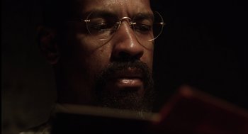 Movie still from “The Hurricane” (1999), directed by Norman Jewison – A person wearing glasses and reading a book; Close Up shot, Low angle